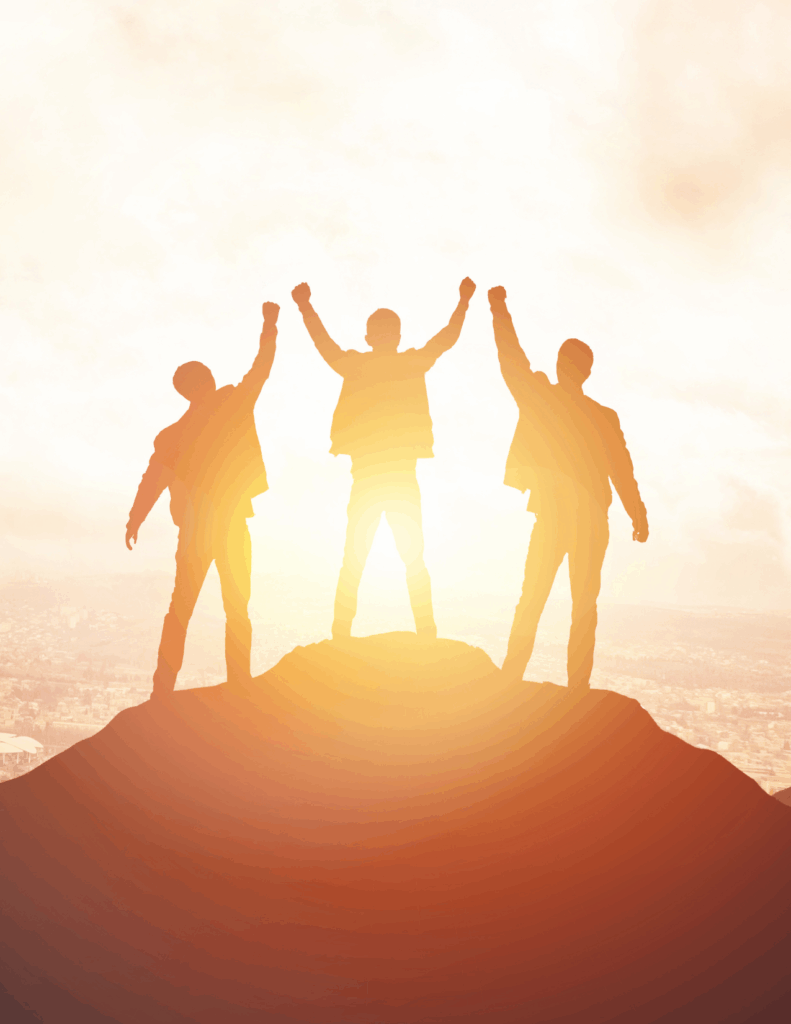Three people stand triumphantly on a hilltop at sunrise or sunset, raising their arms in celebration against a bright, glowing sky.