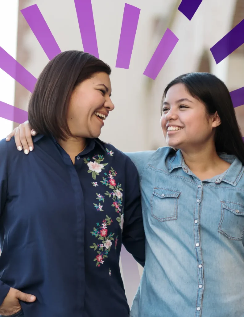 Two women stand side by side, smiling at each other with arms around shoulders; purple graphic rays are illustrated behind them.