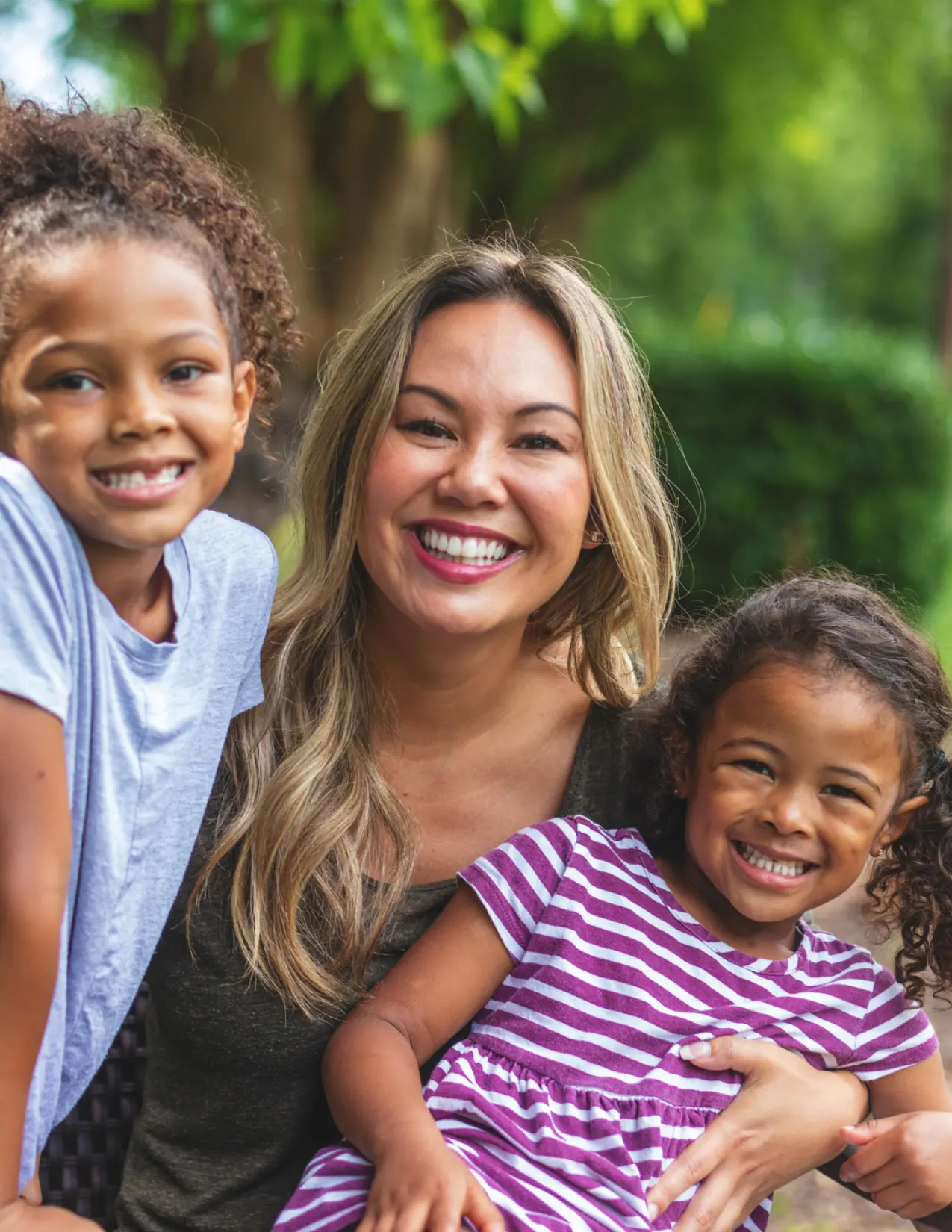 A mom with her two daughters smiling